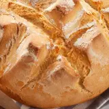 Pan rápido Thermomix, dorado y crujiente, con cortes en forma de rombos y espolvoreado de harina.