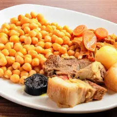 Plato de cocido en olla express con garbanzos, carne, morcilla, patatas y verduras.