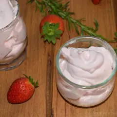 Delicioso postre con fresas, cremoso y ligero, servido en copas. Fresas frescas y romero decoran la mesa de madera.