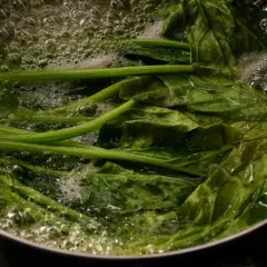 Espinacas frescas hirviendo en una olla. El tiempo de cocción de las espinacas es corto para mantener su frescura.