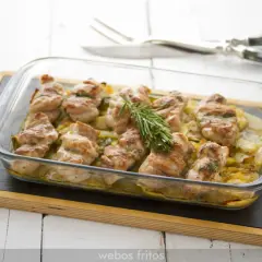 Contramuslos de pollo al horno crujientes, dorados y jugosos, servidos en una fuente de cristal con patatas y romero.