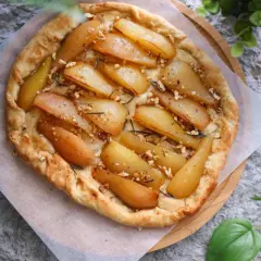 Deliciosa tarta de pera rústica, con trozos de pera caramelizada, nueces y romero, sobre una base dorada y crujiente.