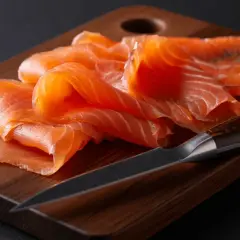 Finas lonchas de salmón ahumado sobre tabla de madera. Se puede congelar el salmón ahumado para conservarlo fresco.