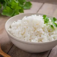 Un tazón de arroz blanco recién cocido, decorado con cilantro fresco. ¿Te preguntas cuánto dura el arroz en la nevera?