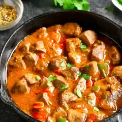 Sabroso pollo guisado arguiñano en sartén, con pimientos y especias. ¡Un plato casero que huele delicioso!