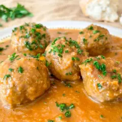 Cinco deliciosas albóndigas al horno en una rica salsa, espolvoreadas con perejil fresco. ¡Perfectas para mojar pan!