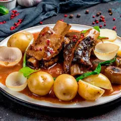 Costillas al horno con patatas, cebolla y un toque de vino blanco. Un plato jugoso y lleno de sabor.