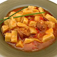 Patatas a la riojana arguiñano, un plato casero con trozos de patata, chorizo y pimiento en una salsa roja, decorado con cebollino.