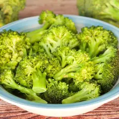 Brocoli al microondas en un cuenco azul sobre madera.