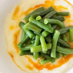 Judías verdes frescas y tiernas sobre una cremosa base de puré de patatas, con un toque de aceite de pimentón.