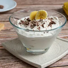 Delicioso mousse de plátano cremoso, adornado con trozos de chocolate y rodajas de plátano fresco.