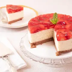 Deliciosa tarta de fresa con una capa cremosa y cobertura de gelatina de fresa, decorada con menta. Una porción ya servida en un plato.