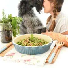 Guisantes con jamón, un plato sencillo y delicioso preparado en Thermomix. Una mujer y su perro disfrutan de la comida.