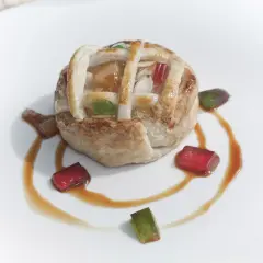 Deliciosa tarta de Mondoñedo, con su masa dorada y relleno de frutas, decorada con gominolas de colores y un sirope dulce.