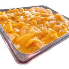 Bandeja metálica llena de trozos de pollo marinados en una salsa anaranjada, listos para convertirse en deliciosos pinchitos.