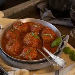 Sabrosas polpette al sugo, jugosas albóndigas en salsa de tomate, adornadas con albahaca fresca.