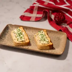 Dos porciones de pastel de cabracho, cubiertas con mayonesa y cebollino, servidas en una bandeja rústica.