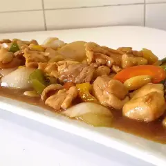 Delicioso pollo con almendras, pimientos y cebolla en una salsa dorada.