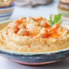 Cremoso hummus de garbanzos, decorado con garbanzos enteros, pimentón y perejil. Perfecto para dipear.