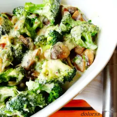 Brocoli con champiñones gratinados en una cazuela blanca, cubiertos de una cremosa salsa de queso.