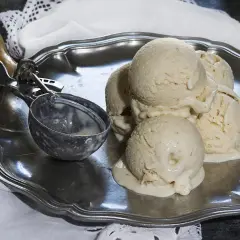 Cremoso helado de plátano derritiéndose en una bandeja de plata, junto a un cucharón.