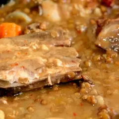 Un plato humeante de lentejas con costillas, con trozos de zanahoria y un caldo espeso y sabroso.