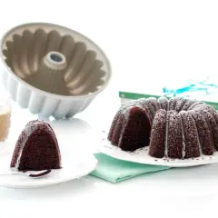 Bizcocho chocolate Thermomix, recién horneado y decorado con glaseado blanco. Un trozo ya servido con un vaso de leche.