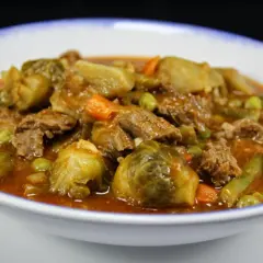 Un reconfortante plato de menestra de verduras con carne de la abuela, lleno de tiernos trozos de carne, coles de Bruselas, zanahorias y judías verdes en una rica salsa.