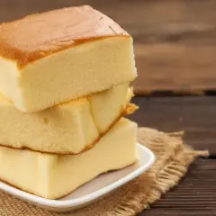 Tres porciones de bizcocho sin levadura apiladas en un plato blanco sobre una tela de arpillera.