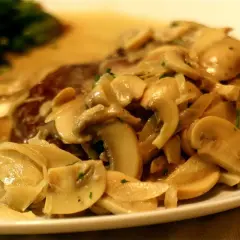 Un delicioso lomo con champiñones en salsa cremosa, acompañado de espinacas. ¡Un plato principal irresistible!