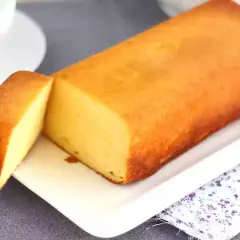 Un delicioso bizcocho de leche condensada, dorado y esponjoso, servido en una bandeja blanca.
