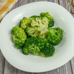 Brocoli al vapor, fresco y verde, servido en un plato blanco. Un toque saludable y delicioso.