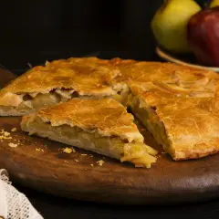 Empanada de manzana de la abuela, dorada y casera, servida en tabla de madera.