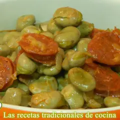Un plato humeante de habas tiernas con rodajas de chorizo español, todo bañado en una salsa sabrosa.