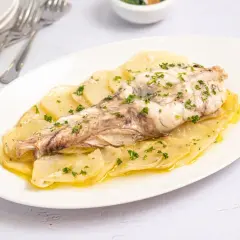 Rape al horno servido sobre patatas laminadas y espolvoreado con perejil fresco. Un plato sencillo y delicioso.