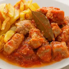 Magro con tomate, la receta de la abuela, servido con patatas fritas doradas. Un plato casero lleno de sabor.