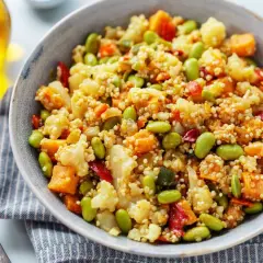 Un tazón de quinoa con verduras coloridas: edamame, coliflor, zanahoria y pimiento rojo. Un plato saludable y delicioso.