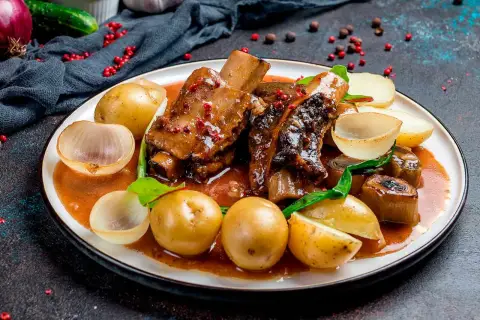 Costillas al horno con patatas, cebolla y un toque de vino blanco. Un plato jugoso y lleno de sabor.