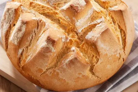 Pan rápido Thermomix, dorado y crujiente, con cortes en forma de rombos y espolvoreado de harina.