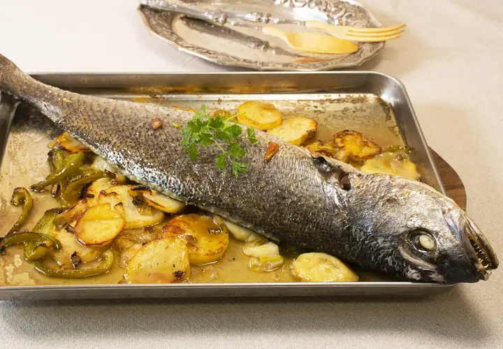 Corvina al horno con patatas y pimientos, lista para servir.