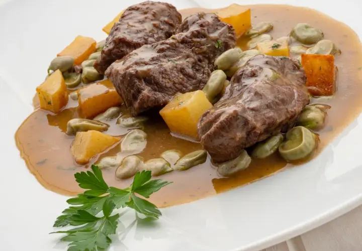 Carrilleras al horno, un plato de Karlos Arguiñano, con habas y trozos de calabaza en una salsa sabrosa.
