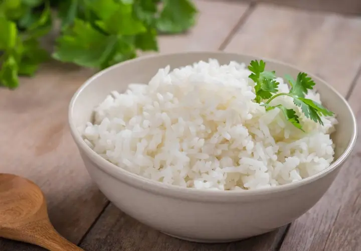 Un tazón de arroz blanco recién cocido, decorado con cilantro fresco. ¿Te preguntas cuánto dura el arroz en la nevera?