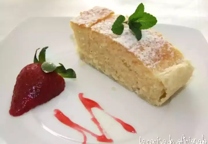 Un delicioso bizcocho de almendras espolvoreado con azúcar glas, decorado con una fresa y menta.