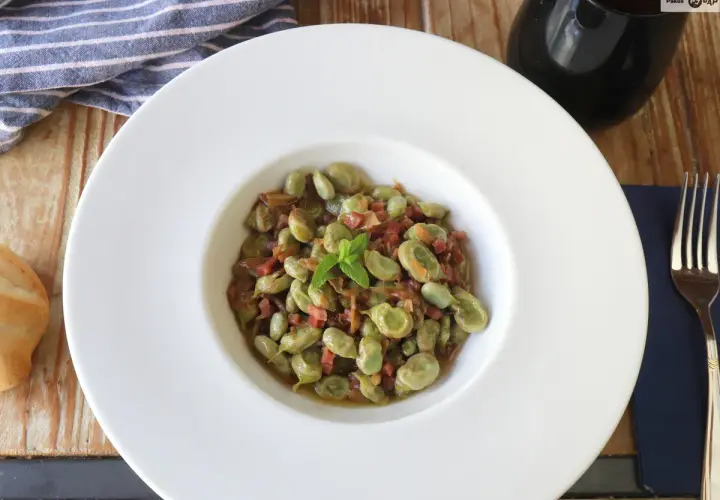 Plato de habas tiernas con jamón, ideal para tus recetas de habas. Servido en un cuenco blanco con menta fresca.