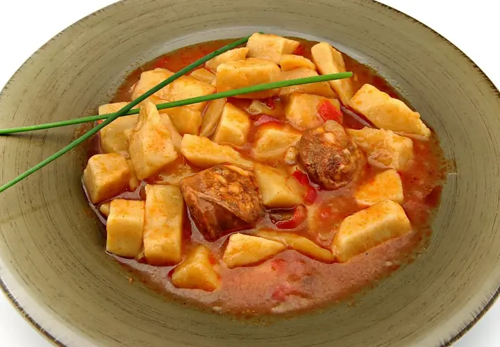 Patatas a la riojana arguiñano, un plato casero con trozos de patata, chorizo y pimiento en una salsa roja, decorado con cebollino.
