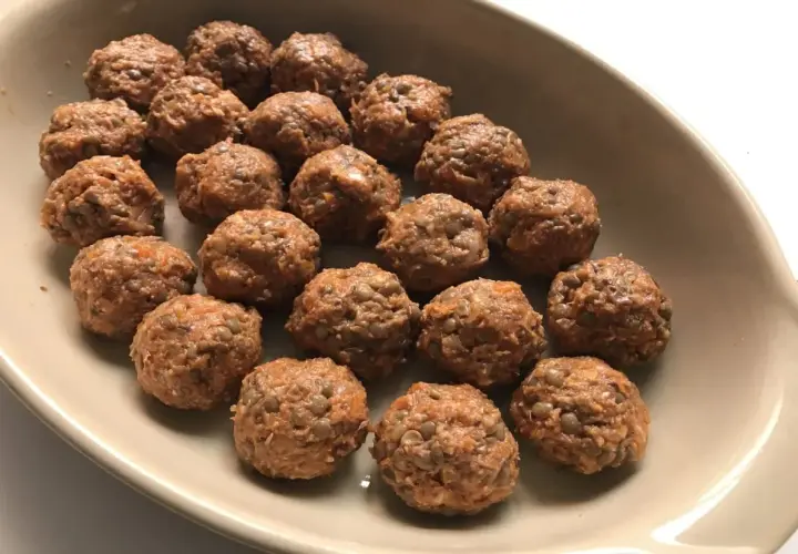 Albondigas de lentejas listas para hornear en una bandeja.