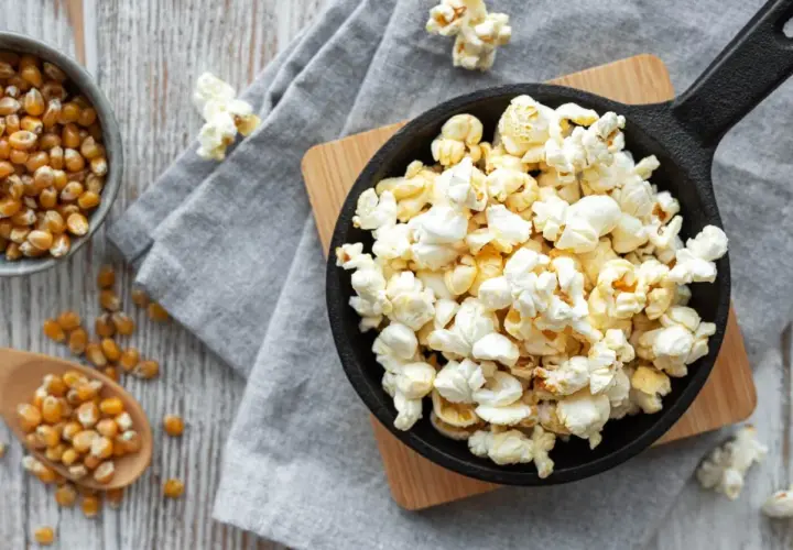 Palomitas recién hechas en sartén, listas para disfrutar. Maíz de palomitas en un cuenco y cuchara de madera.