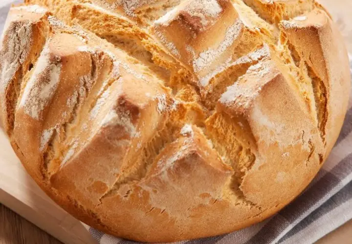 Pan rápido Thermomix, dorado y crujiente, con cortes en forma de rombos y espolvoreado de harina.