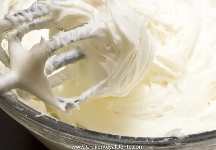 Batidora mezclando un cremoso frosting de queso, listo para decorar.