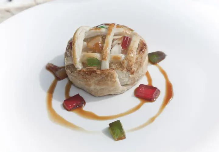 Deliciosa tarta de Mondoñedo, con su masa dorada y relleno de frutas, decorada con gominolas de colores y un sirope dulce.